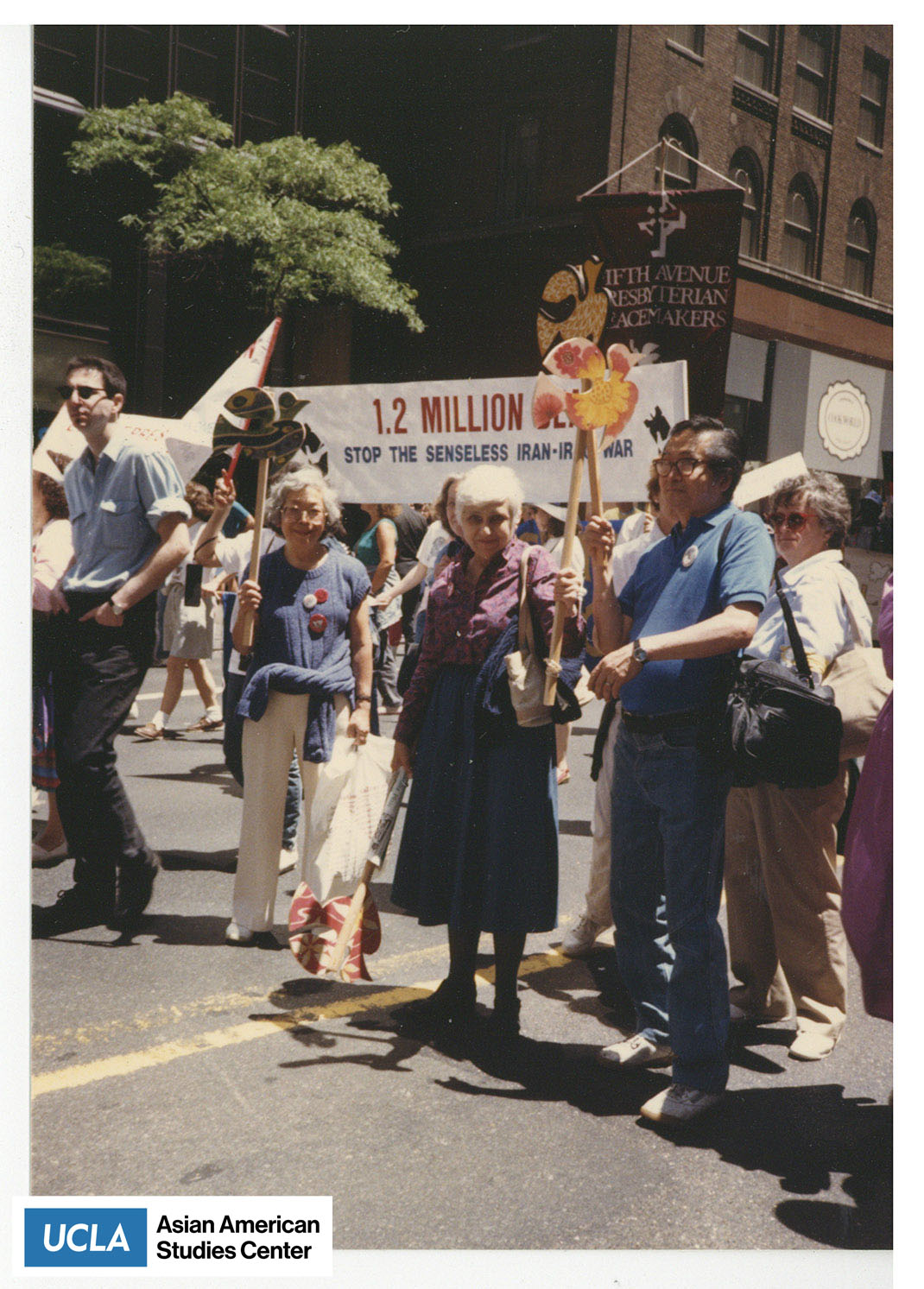 Photograph of a protest of the Iran-Iraq War. People are holding pickets and wooden doves for peace.